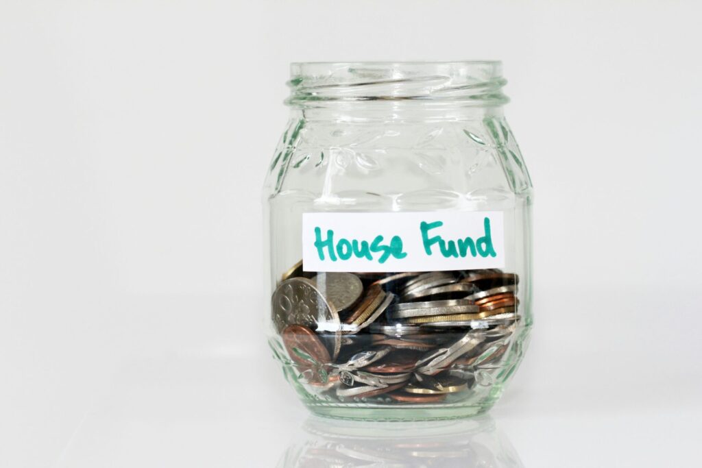 A glass jar of coins labeled house fund