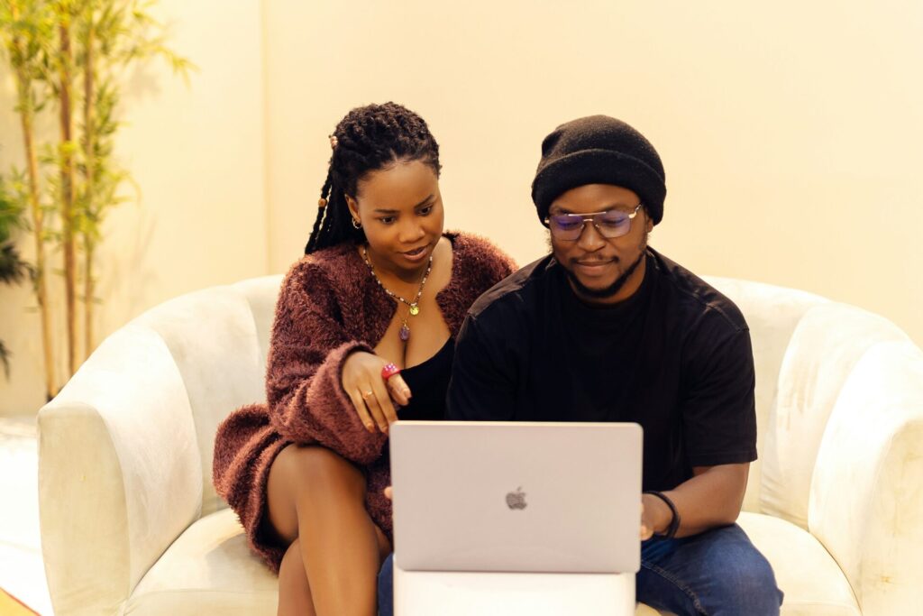 A couple sits together in a cream armchair and looks at a laptop