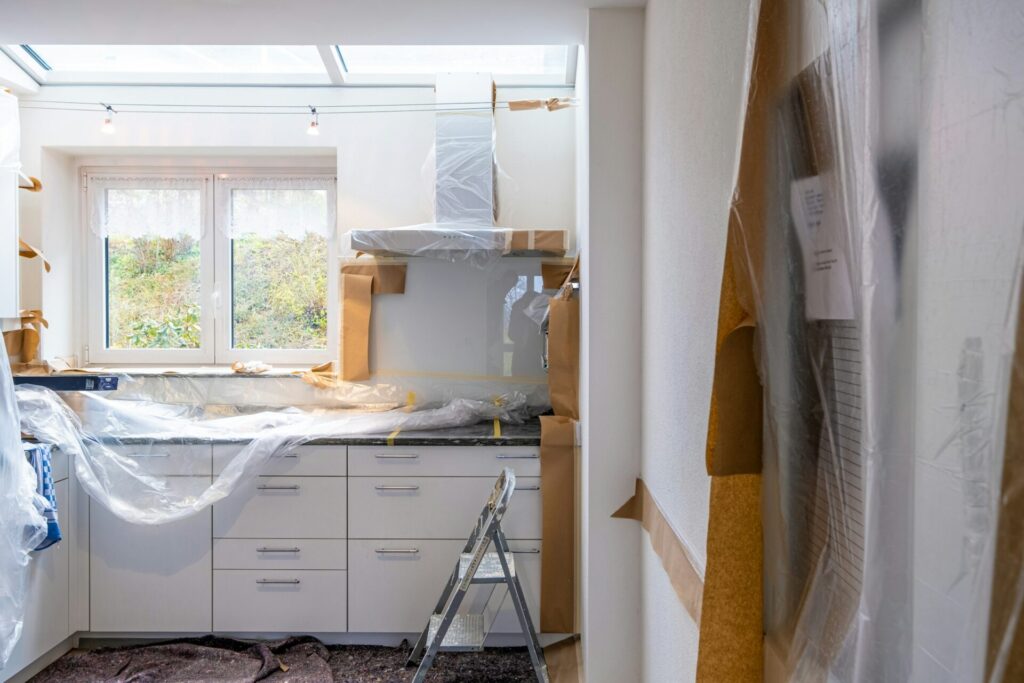 A kitchen mid-renovation with cabinets covered in plastic