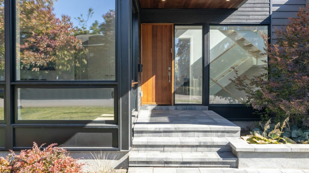 Warm wood front door and stone steps of a modern home in autumn light