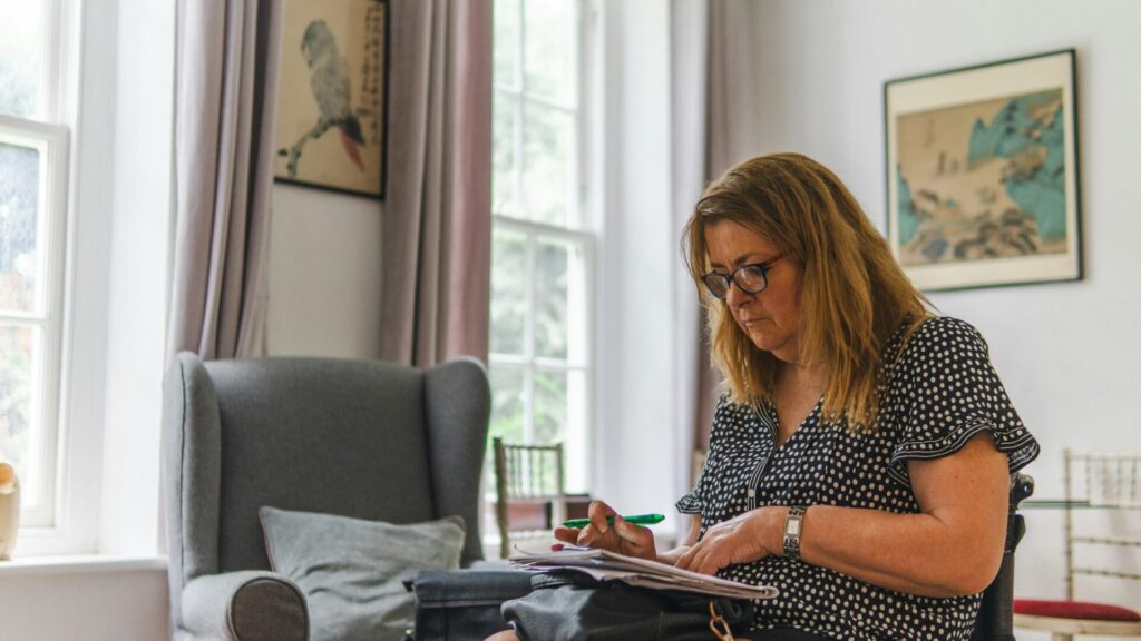 Woman in a wheelchair at home going through paperwork in a bright living room